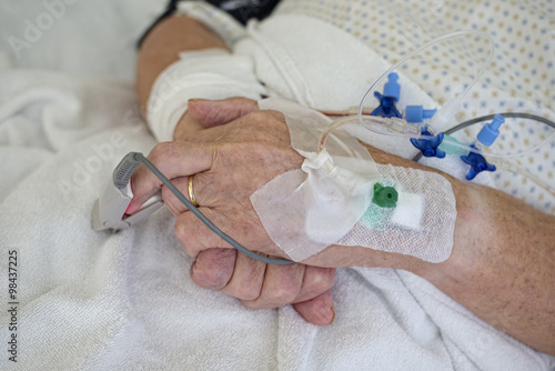 Hands of senior man with cannulae and band-aid being in intensive care photo