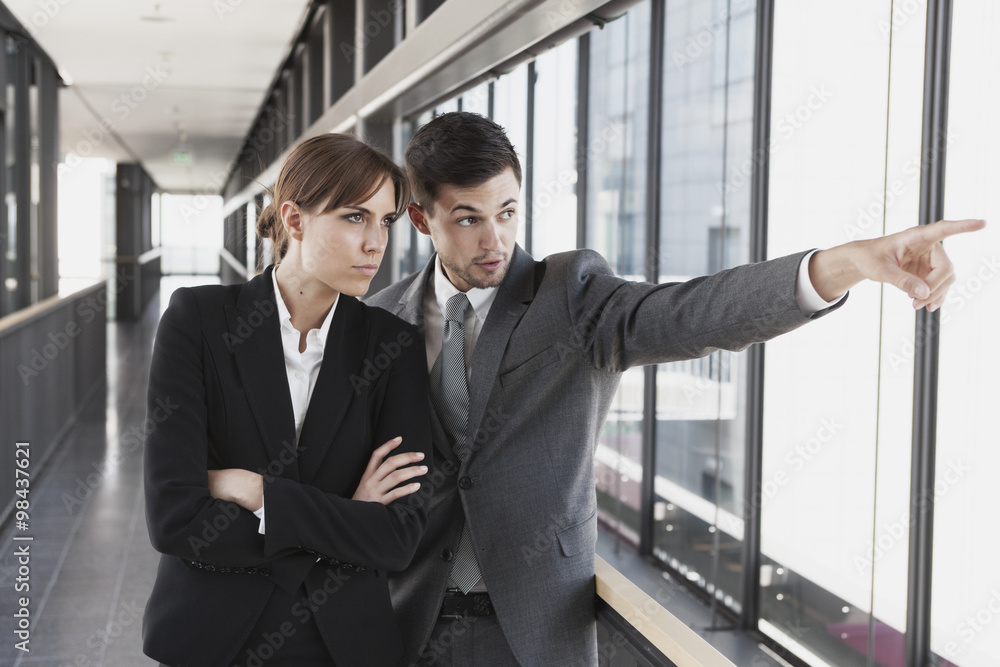 Businessman and businesswoman looking out of window Businessman and businesswoman looking out of window