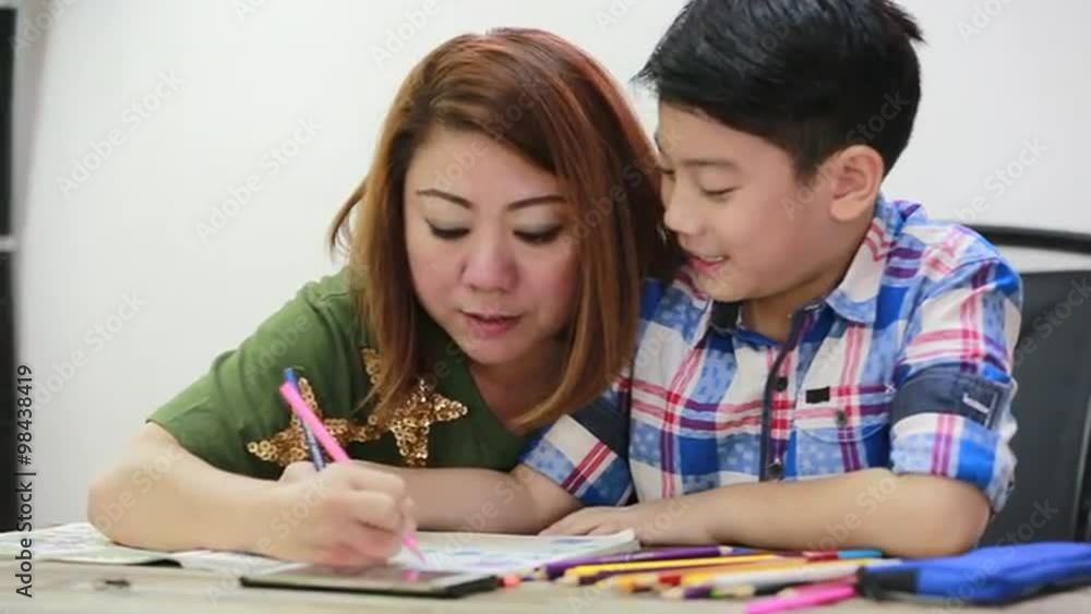Happy asian family boy and parent looking cellphone and drawing together Happy asian family boy and parent looking cellphone and drawing together