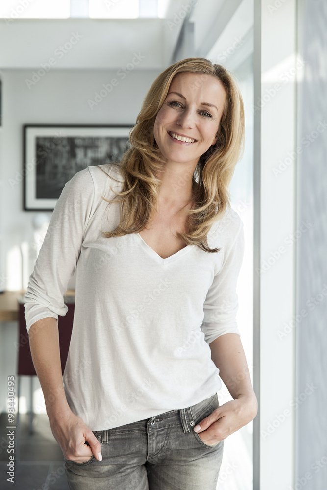 Portrait of happy woman standing in her bright modern home Portrait of happy woman standing in her bright modern home