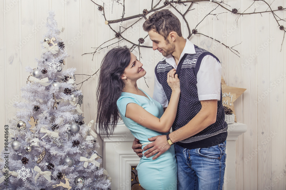 Beautiful couple man and woman hugging in the Christmas interior