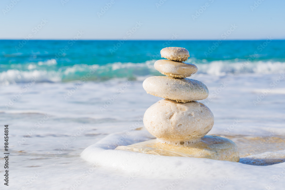 Fototapeta premium Stones pyramid on sand symbolizing zen, harmony, balance. Ocean