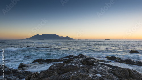 Cape Town Table Mountain's iconic flat top seen from Blouberg Strand in South Africa during sunset.