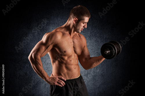 muscular young man lifting weights © romanolebedev