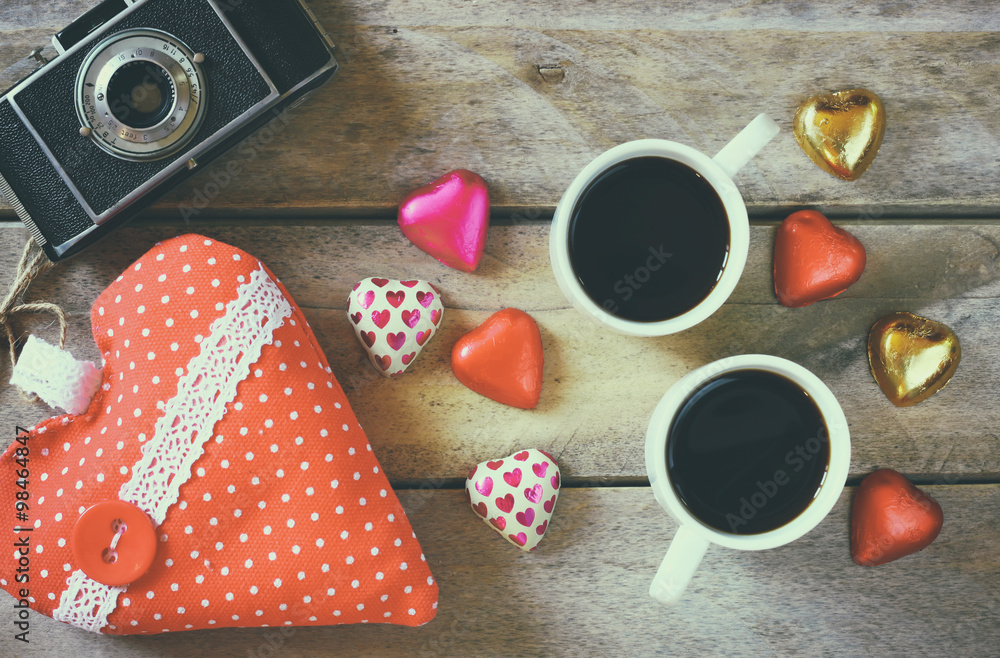 top view image of colorful heart shape chocolates, fabric heart, vintage photo camera and cup of coffee on wooden table. valentine's day celebration concept. retro filtered and toned
top view image of colorful heart shape chocolates, fabric heart, vintage photo camera and cup of coffee on wooden table. valentine's day celebration concept. retro filtered and toned