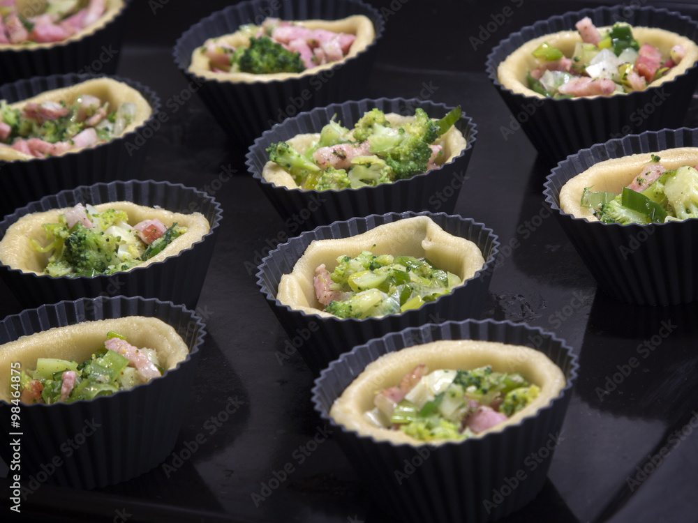 Cooking homemade tartlets with bacon, leeks, broccoli and cheese Cooking homemade tartlets with bacon, leeks, broccoli and cheese
