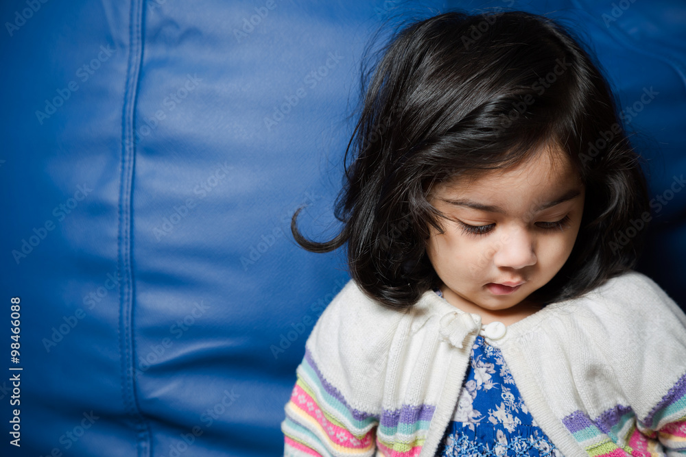 Baby girl sitting beside a sofa wearing a sweater. Baby girl sitting beside a sofa wearing a sweater.