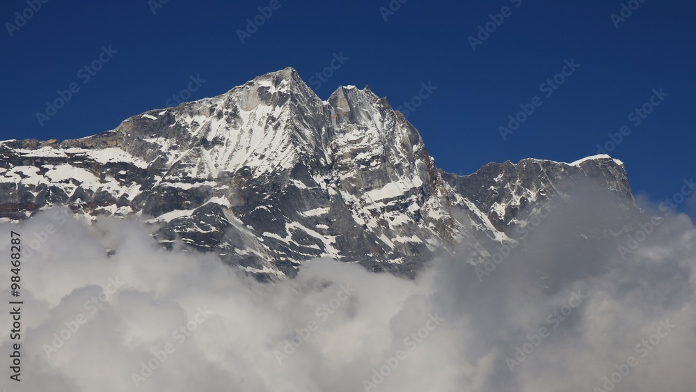 High mountain in the Himalayas reaching out of clouds