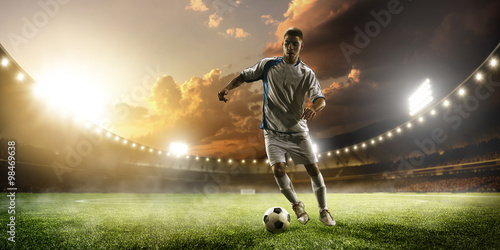 Soccer player in action on sunset stadium panorama background