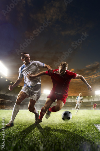 Fototapeta Naklejka Na Ścianę i Meble -  Soccer players in action on sunset stadium background 