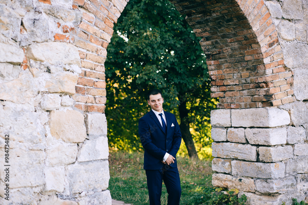 confident, cute groom in a stylish business suit, outdoors, autumn. Portrait of the groom in the park on their wedding day. Rich groom on their wedding day