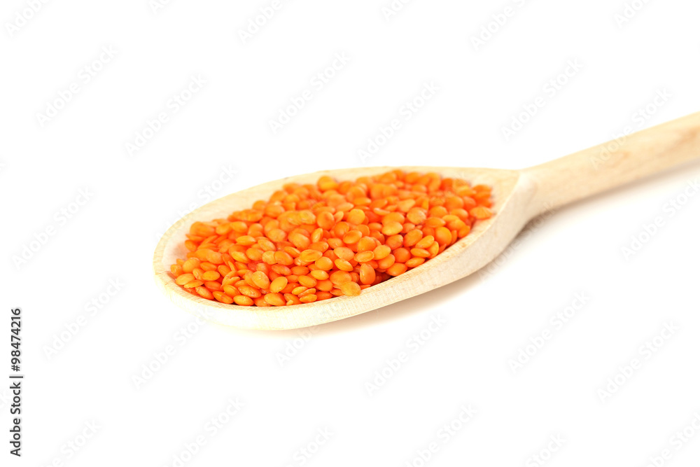 Red lentils in the wooden spoon on a white background Red lentils in the wooden spoon on a white background