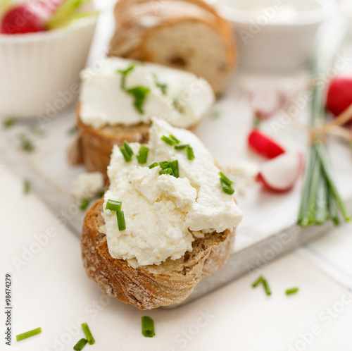 Canapes with curd cheese and fresh chive on a white table. Delicious and healthy breakfast