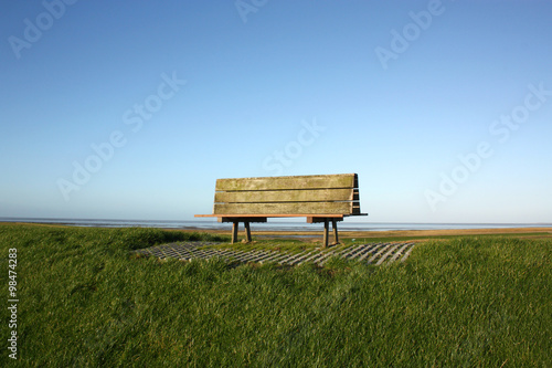 Wooden bench on dike by the sea