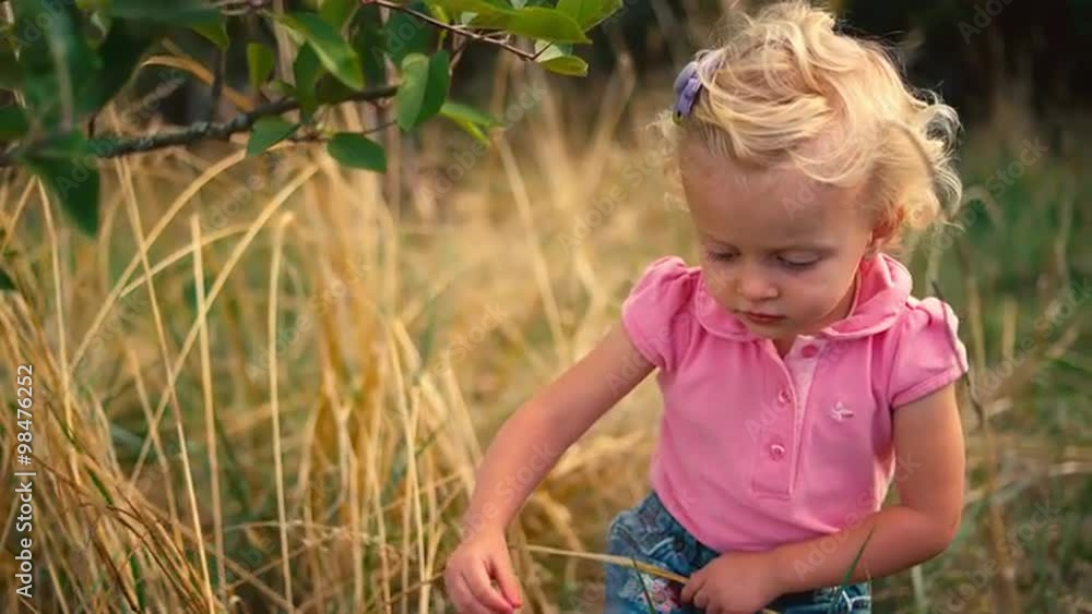 A cute little girl picks an apple off of the ground and trips on her way to put it in a basket A cute little girl picks an apple off of the ground and trips on her way to put it in a basket