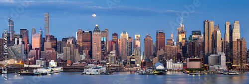 Midtown West Manhattan skyscrapers over the Hudson River. Panoramic view in early evening with moonrise and New York City skyline