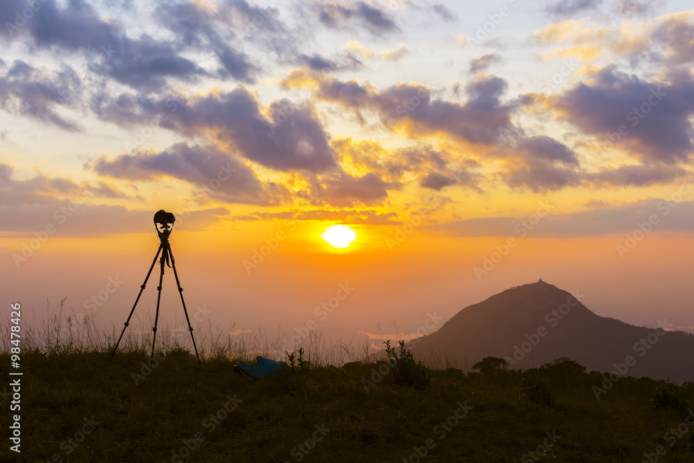 silhouette of a tripod at sunset in the mountains.