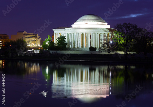 Thomas Jefferson Memorial before sunrise during cherry blossom festival in Washington DC, USA. Colorful reflection of the memorial in waters of Tidal Basin at night.