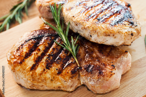 grilled pork chop with rosemary leaf on wooden board