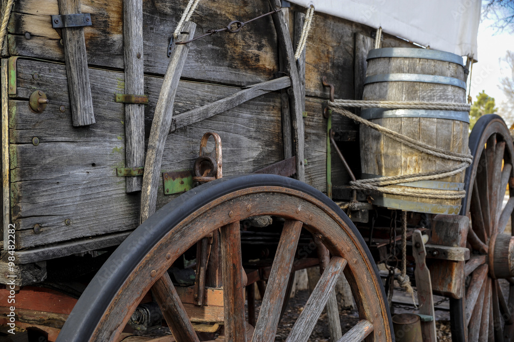 Side  view of pioneer wagon with wheel and water barrel 