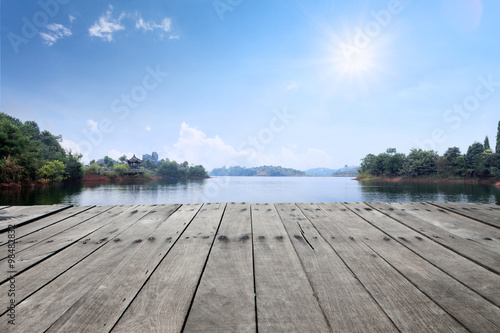 sun skyline and wooden floor on side of lake