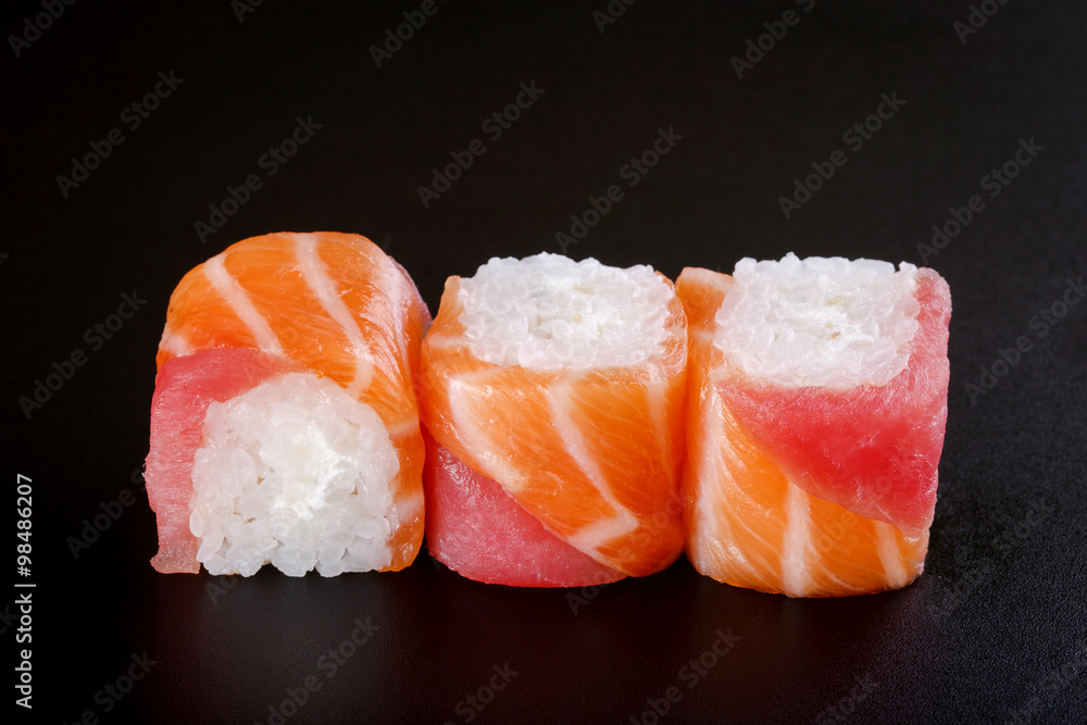 fresh sushi roll with tuna, salmon and cream cheese. On black ba fresh sushi roll with tuna, salmon and cream cheese. On black ba