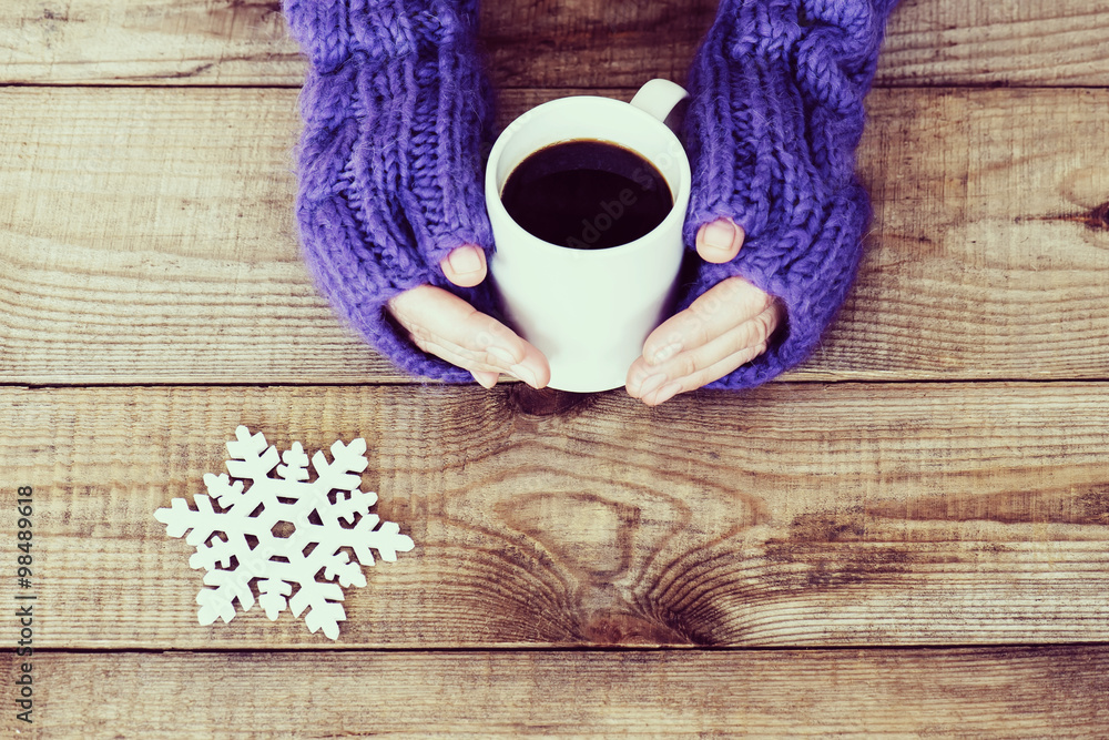 Woman hands in teal gloves are holding a mug with hot coffee or Woman hands in teal gloves are holding a mug with hot coffee or