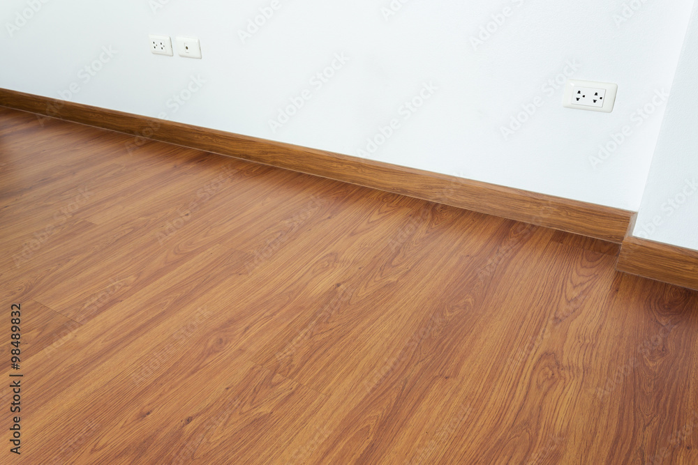 empty room with brown wood laminate floor and white mortar wall empty room with brown wood laminate floor and white mortar wall