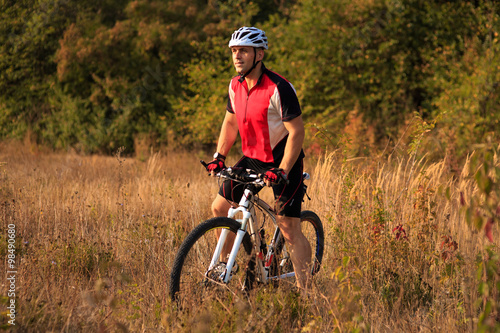 Cyclist with His Bike on the Autumn Meadow