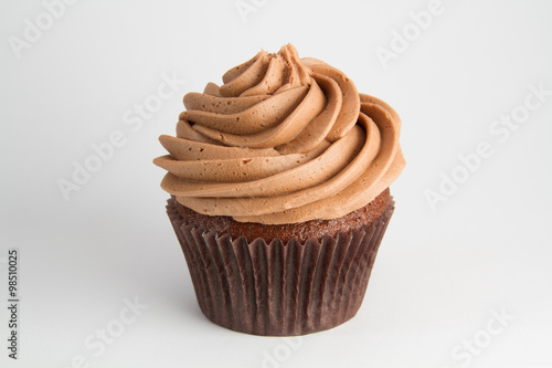 A chocolate cupcake with swirled frosting on a white background.