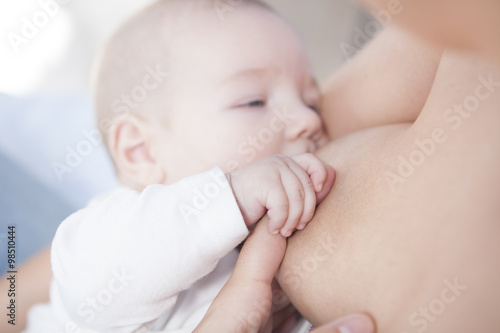 Baby holds her mom hand while he is breastfed