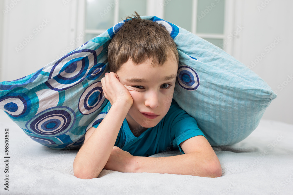 The small boy with alarm clock in the bed