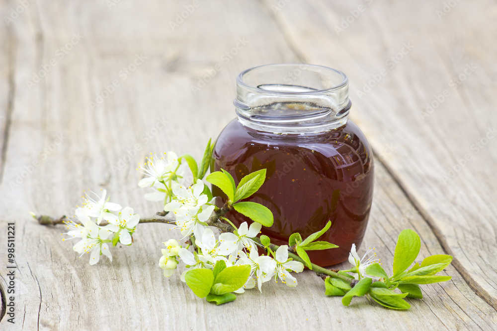 Honey in jar and flowers on wooden background Honey in jar and flowers on wooden background