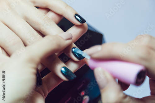 Manicure. Beauty saloon. Close-up. Apply black nail polish.