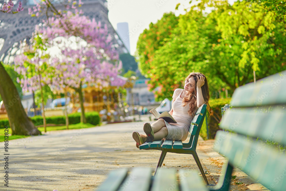Naklejka premium Beautiful young woman in Paris, reading a book