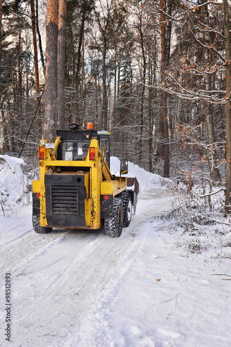 The tractor clears snow from the road