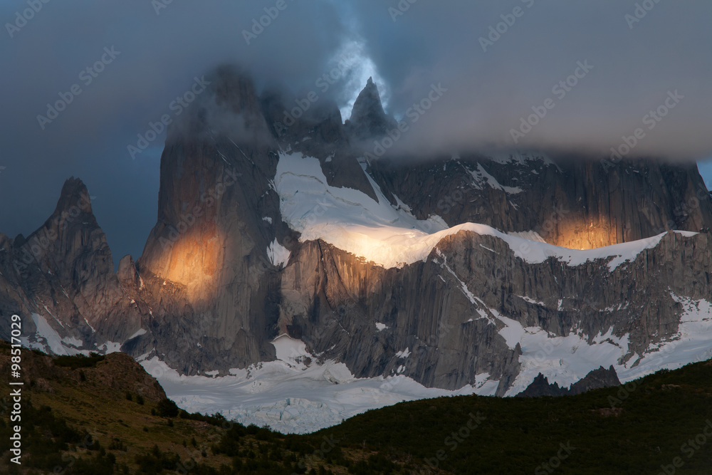 Spots of light on the mountain in the cloud. Mount Fitz Roy. Patagonia. Argentina.