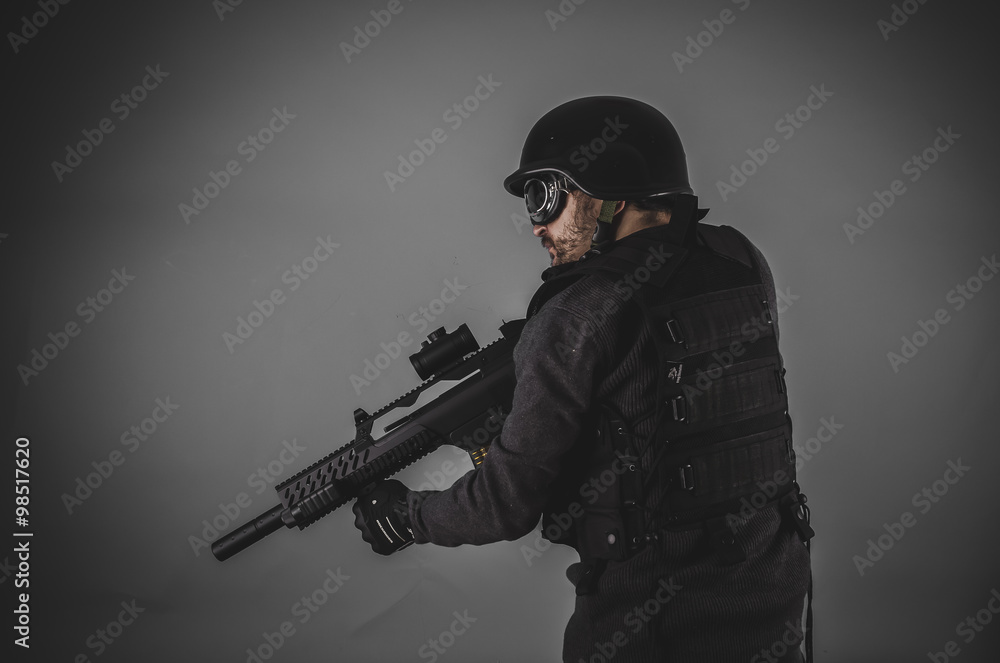 airsoft player with gun, helmet and bulletproof vest on gray bac airsoft player with gun, helmet and bulletproof vest on gray bac
