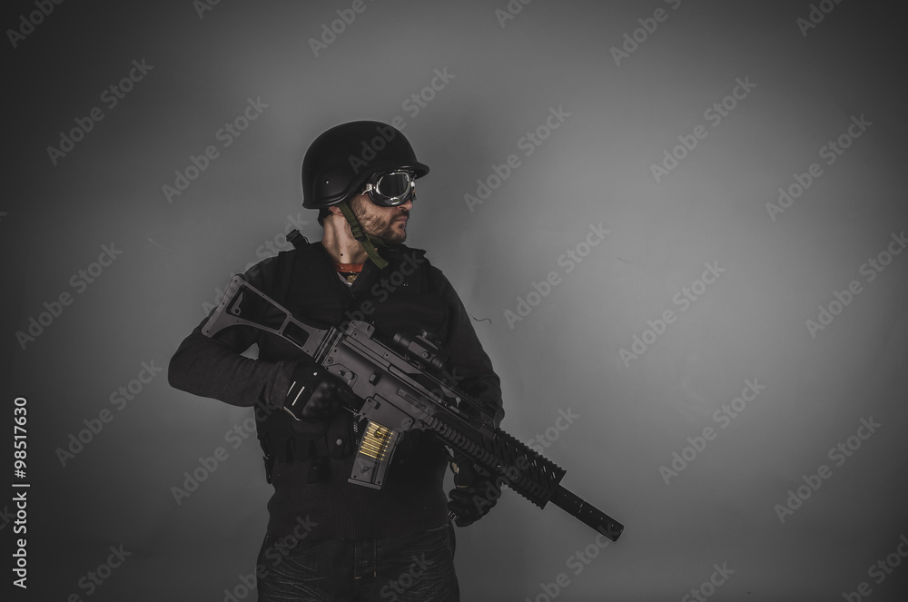 airsoft player with gun, helmet and bulletproof vest on gray bac airsoft player with gun, helmet and bulletproof vest on gray bac