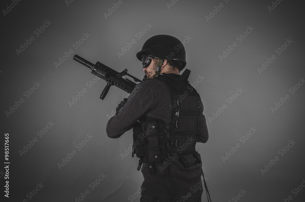 airsoft player with gun, helmet and bulletproof vest on gray bac airsoft player with gun, helmet and bulletproof vest on gray bac