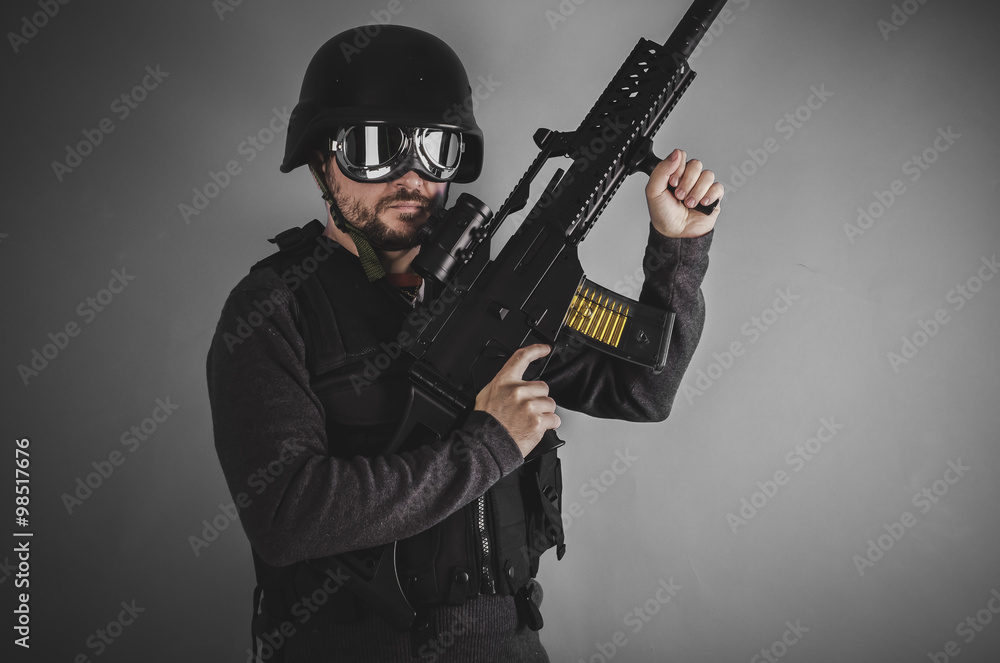 airsoft player with gun, helmet and bulletproof vest on gray bac airsoft player with gun, helmet and bulletproof vest on gray bac