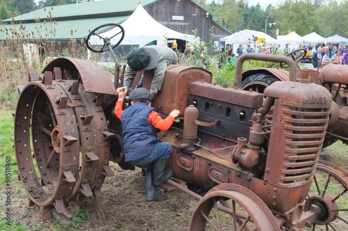 Children playing on an old, rusty farm tractor at 2015 Fall Fair, Salt Spring Island, BC, Canada