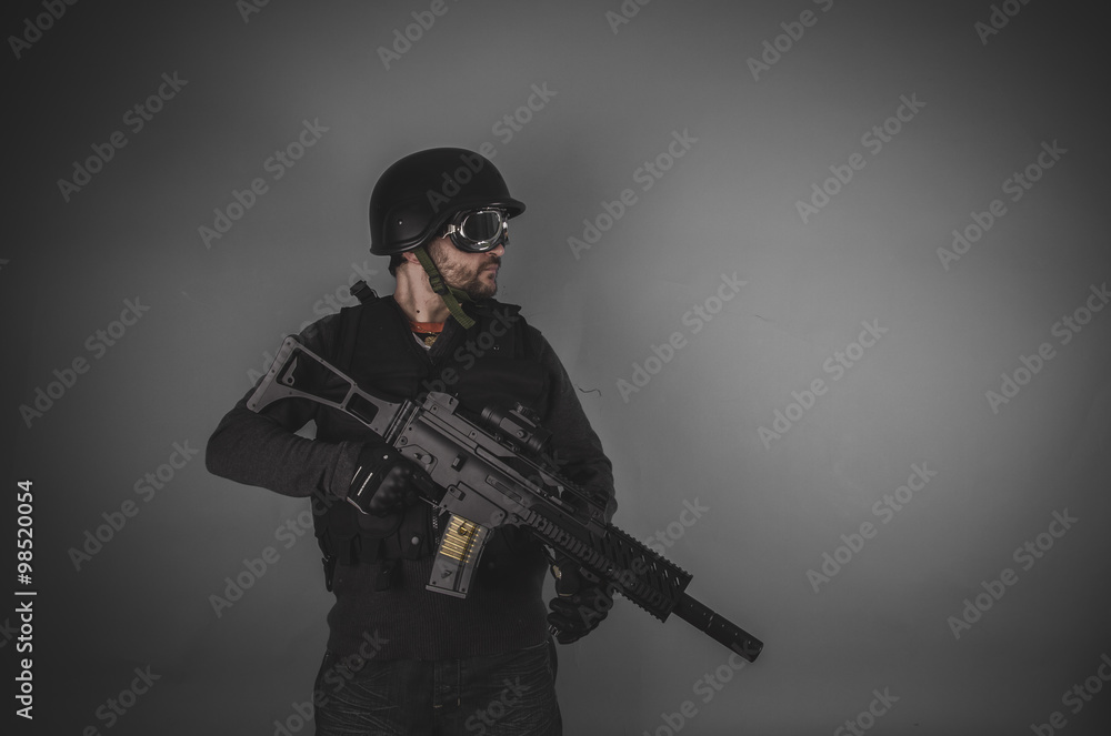 airsoft player with gun, helmet and bulletproof vest on gray bac airsoft player with gun, helmet and bulletproof vest on gray bac