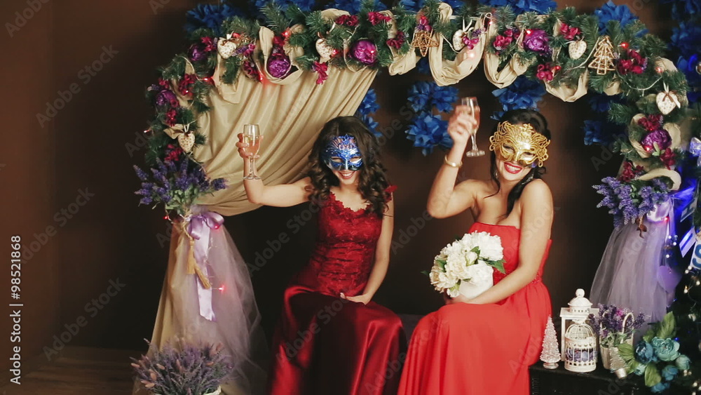 Two beautiful lady in Venetian masks drinking champagne Two beautiful lady in Venetian masks drinking champagne