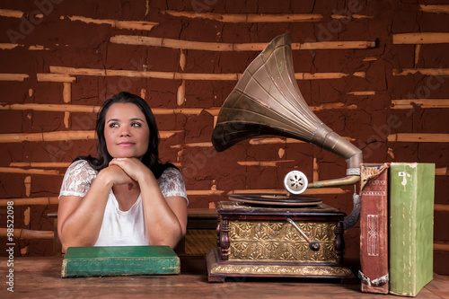 A girl listening to music on an old gramophone with some album discs photo