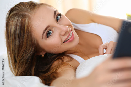 Young smiling beautiful blonde woman lying in bed early in morni