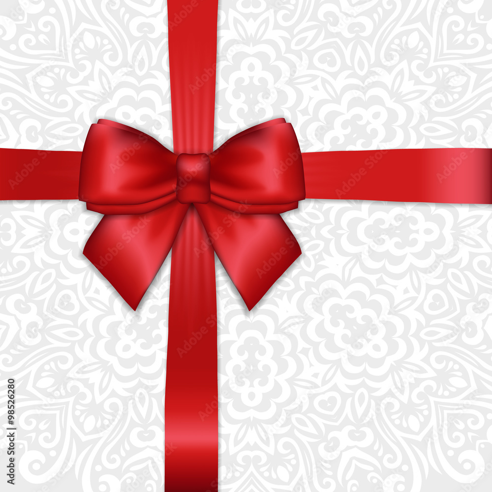 Shiny holiday red satin ribbon bow on white lacy ornamental bac Shiny holiday red satin ribbon bow on white lacy ornamental bac