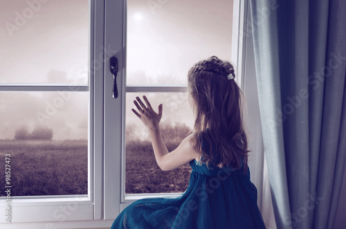 Miserable girl looking through window © konradbak
