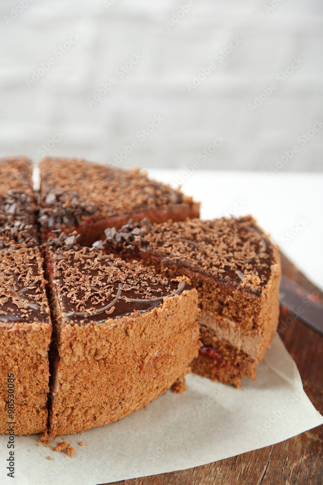 Sliced chocolate cake on wooden table, on light background Sliced chocolate cake on wooden table, on light background