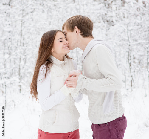 boy kissing girl in winter forest